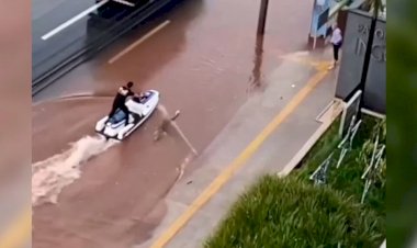 Homem usa jet-ski para andar na rua em dia de chuva forte em Goiânia